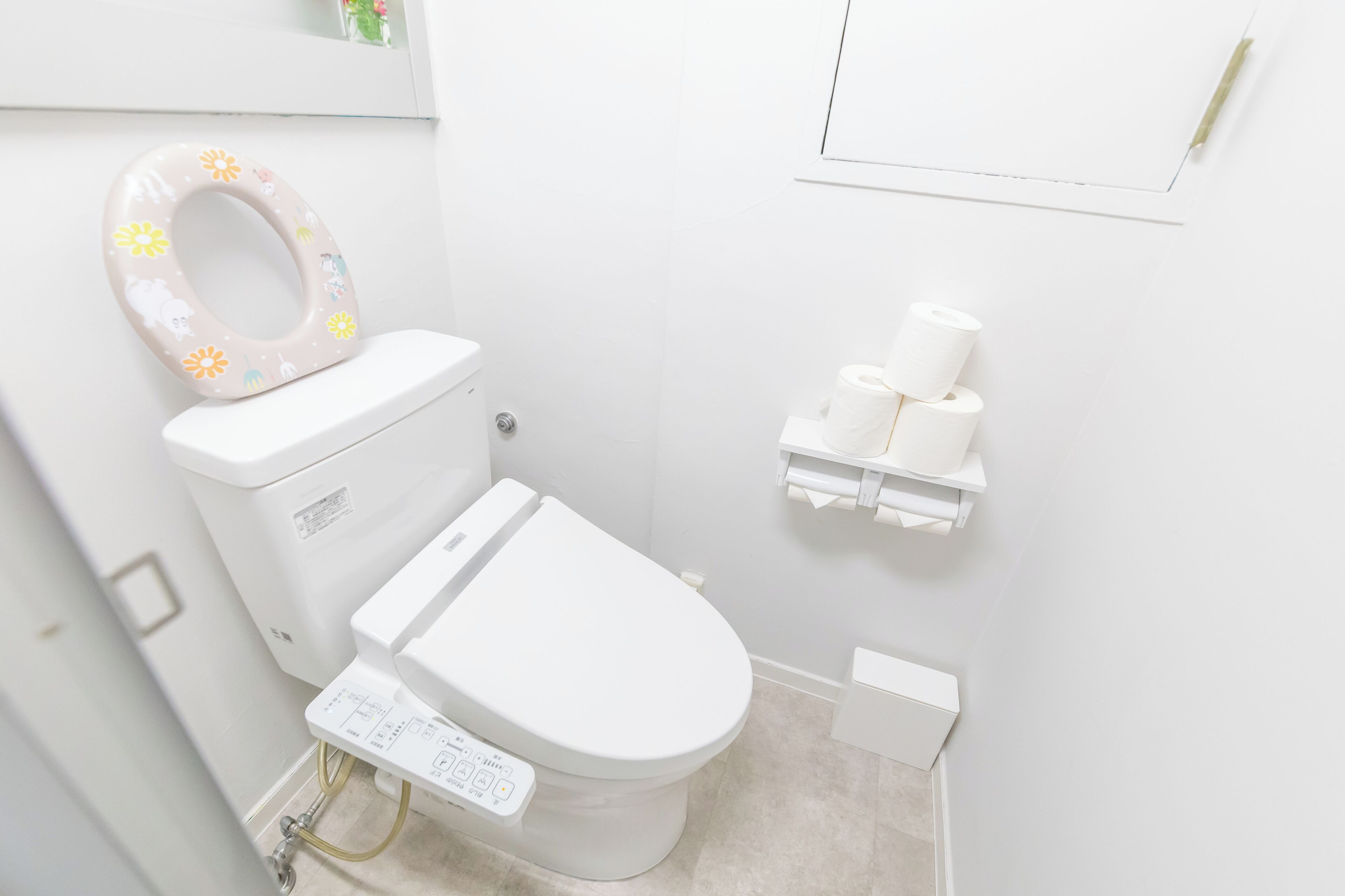 Une salle de bain moderne équipée de toilettes, d’un porte-rouleau et d’un rouleau de papier toilette.