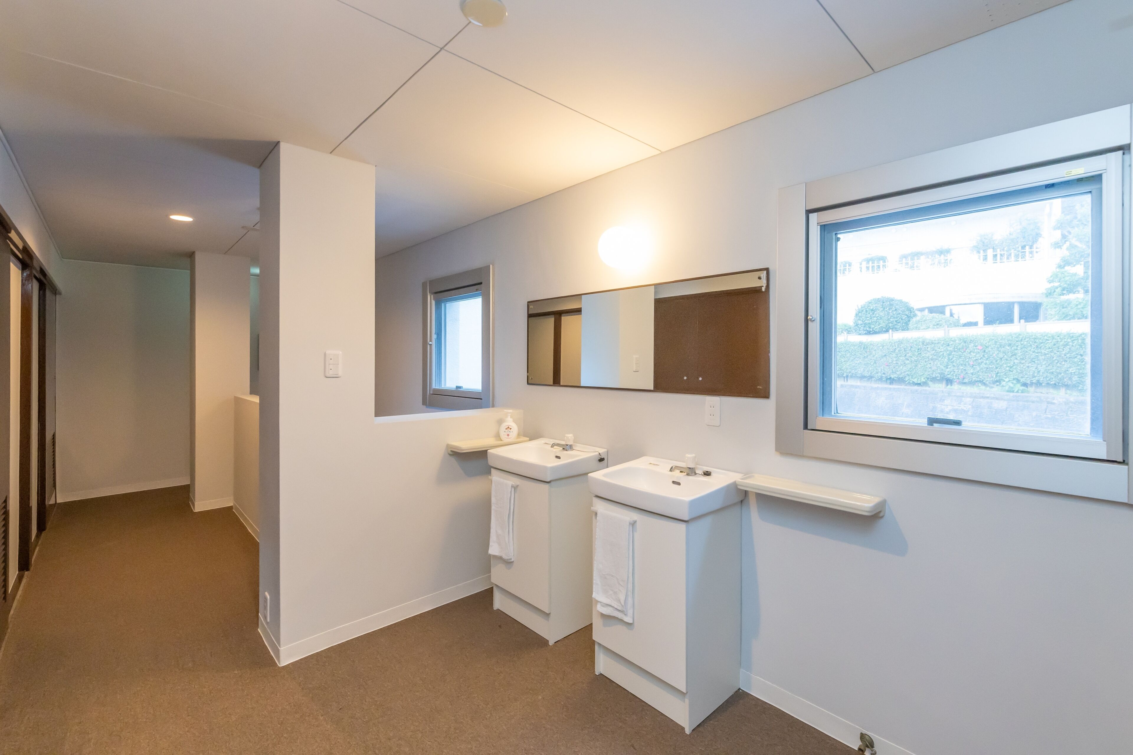 A modern bathroom with two sinks, a mirror, and a window.