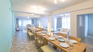 A dining area with a long table set for a meal, a sofa, and a play area in the background. - Shirahama White Beach House (Shirahama)