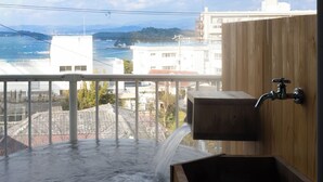A hot tub with a wooden wall and a view of a coastal area. - Shirahama White Beach House (Shirahama)