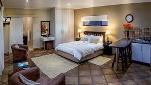 A bedroom with a bed, bedside tables, a desk, a chair, and a bathroom. - Double Bed and Sleeper Couch, Luxury Room, business travel, near Port Elizabeth (Port Elizabeth)
