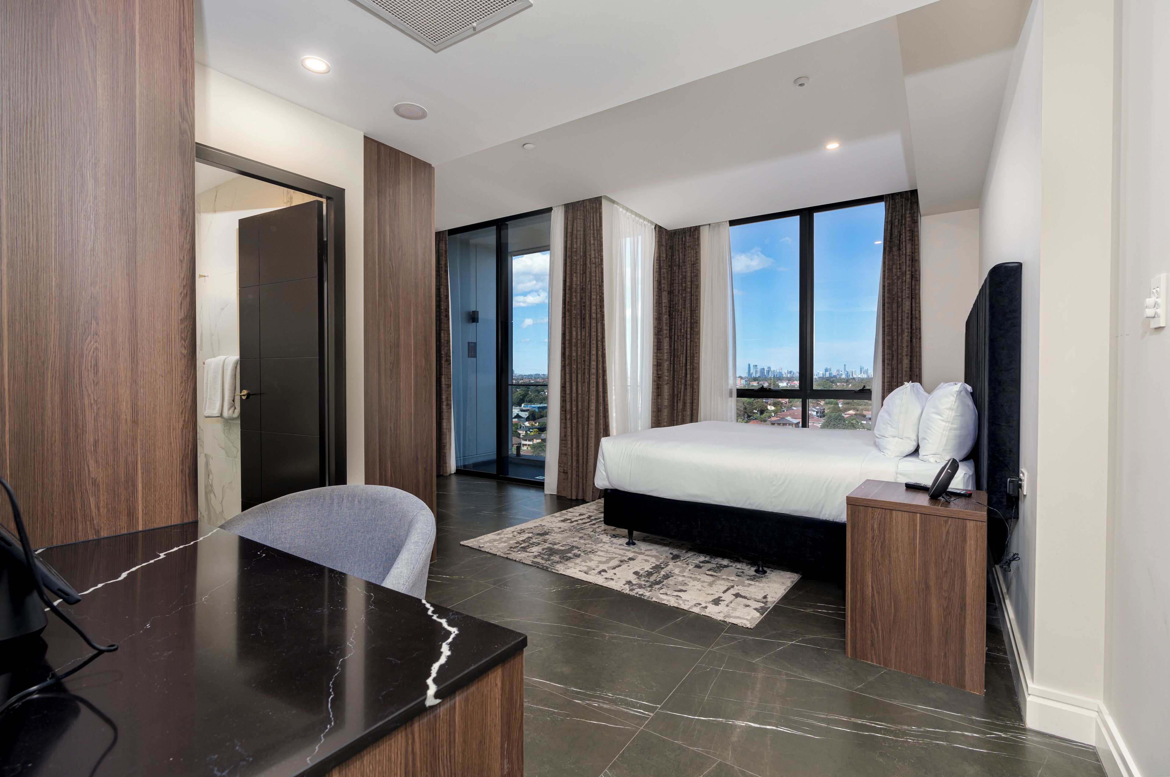 Ein modernes Hotelzimmer mit einem großen Bett, einem Schreibtisch und Blick auf die Stadtlandschaft.