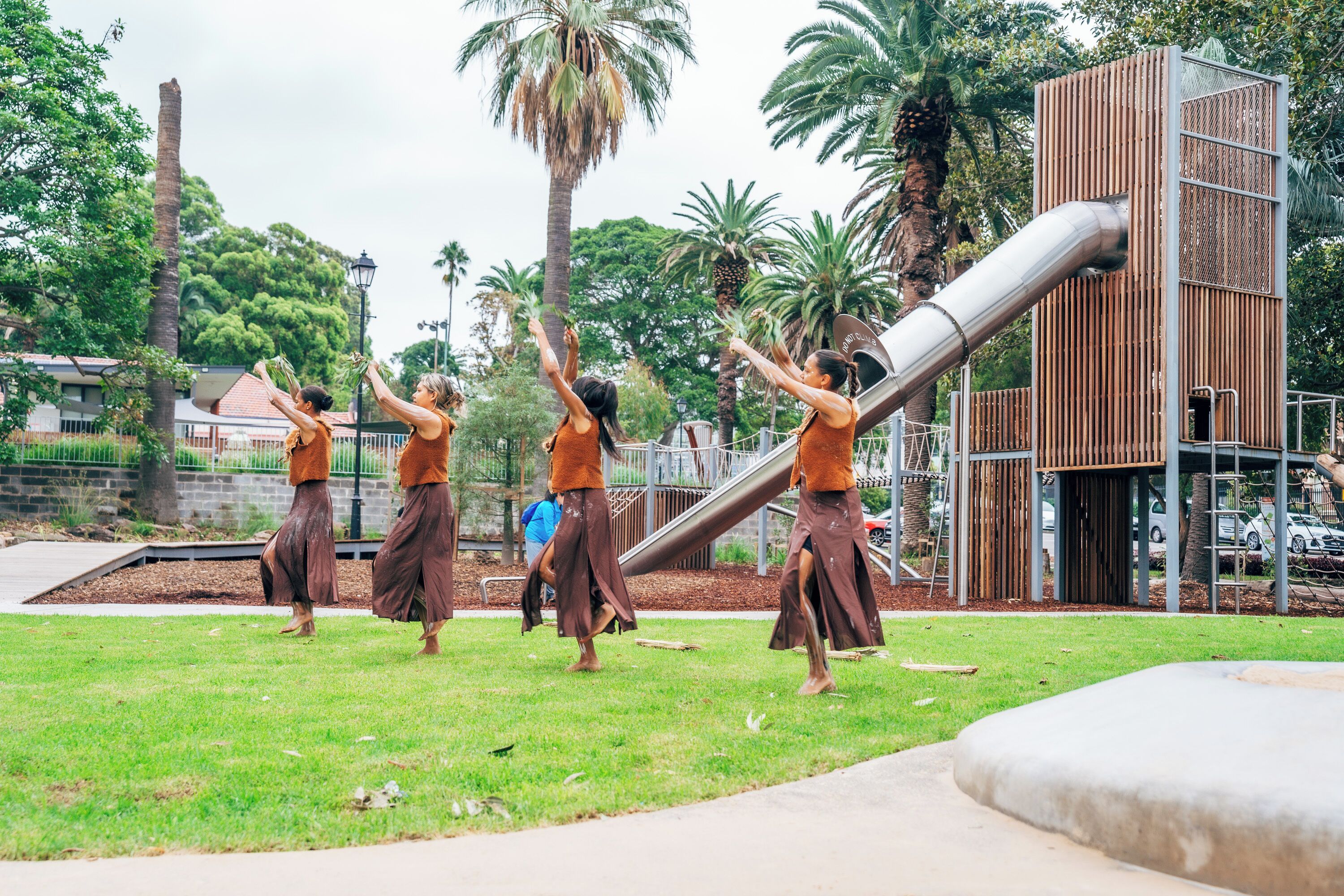 A group of people in a park with a playground structure.