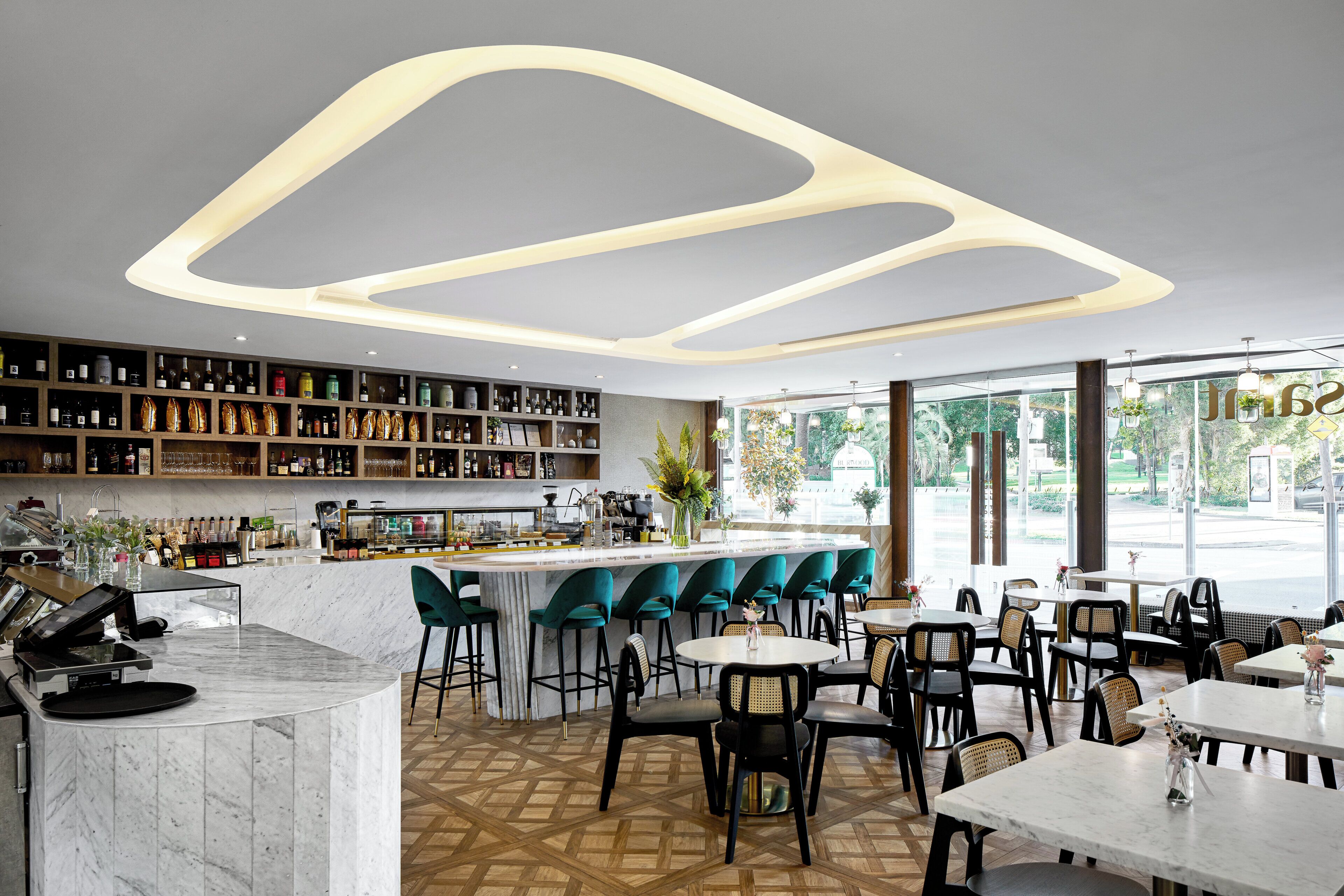 A modern bar area with a marble countertop, bar stools, and a variety of bottles and glasses.
