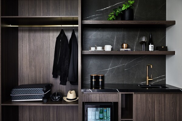Una cocina moderna con armarios de madera oscura, salpicadero de mármol y refrigerador empotrado.