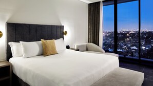 A modern hotel room with a large bed, a view of a cityscape, and a city skyline visible through the window. - Crowne Plaza Sydney Burwood by IHG (Burwood)