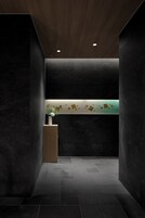 A modern reception area with dark walls, a wooden ceiling, and a reception desk with a vase of flowers.