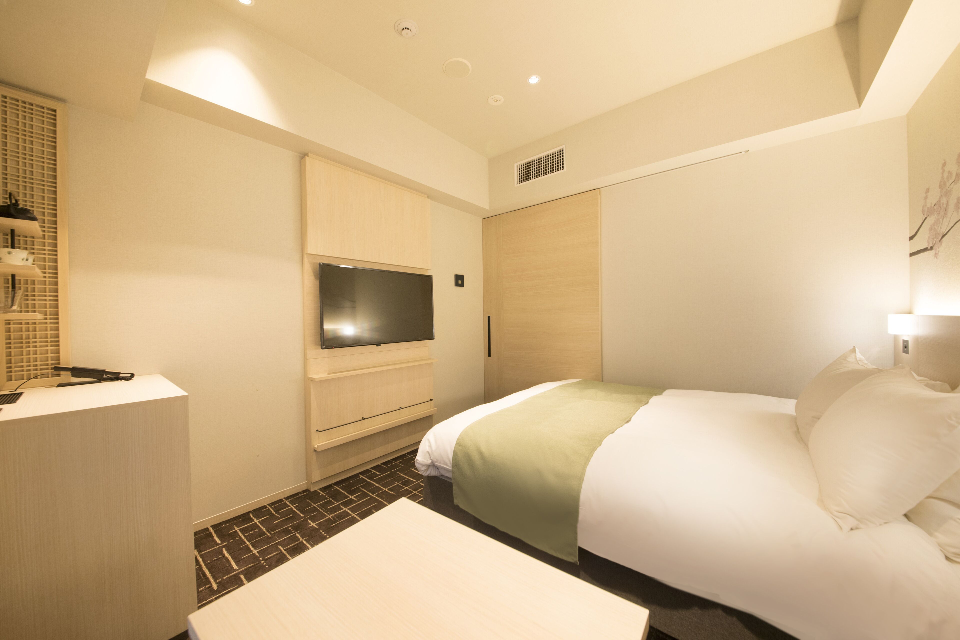 Una habitación de hotel con cama, televisión, escritorio y espejo.