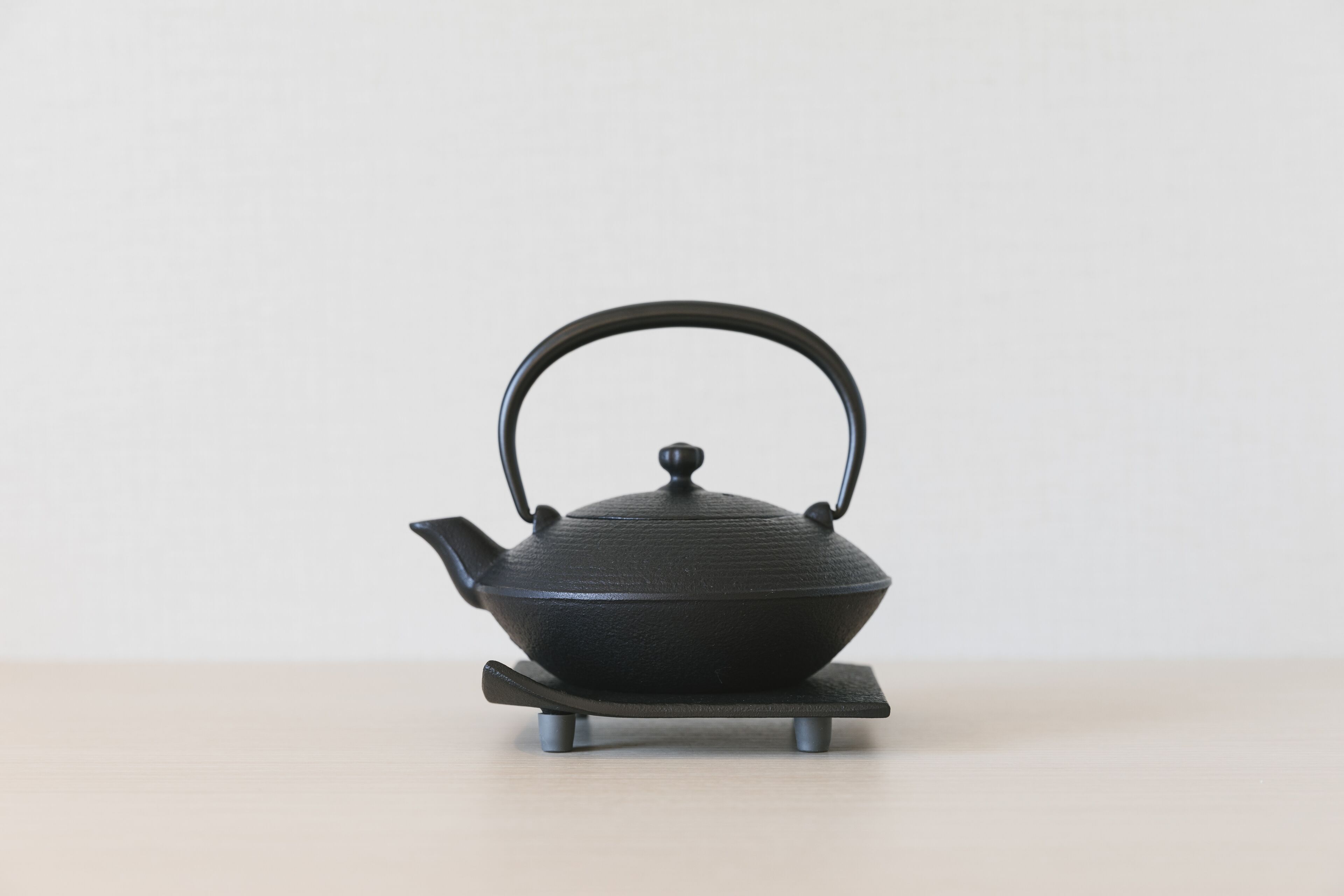 A black teapot on a stand.