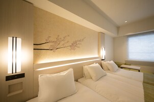 Una habitación de hotel con una cama grande, una mesita de noche y una lámpara de pared.