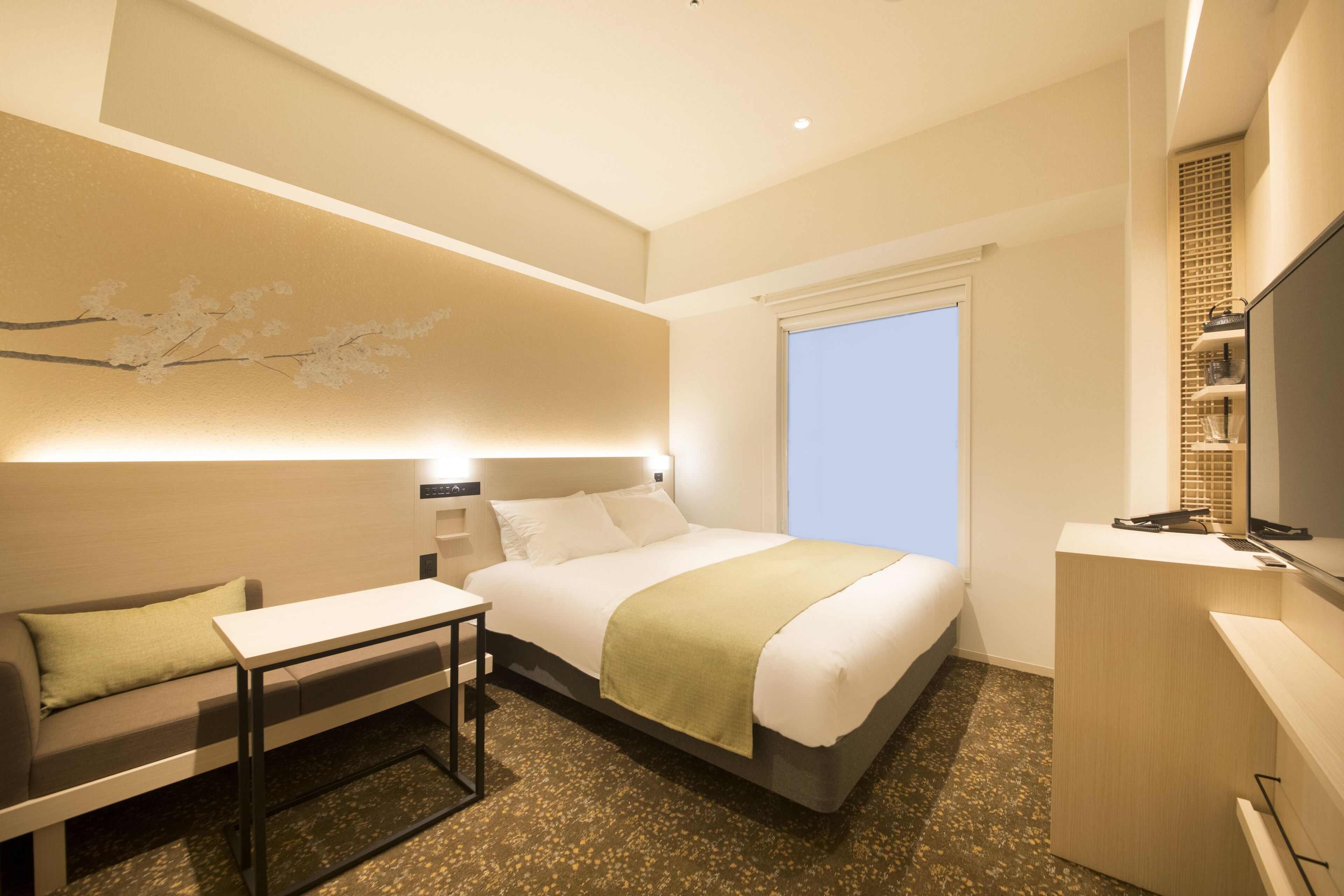 Una habitación de hotel moderna con una cama grande, un escritorio, una silla y un televisor.