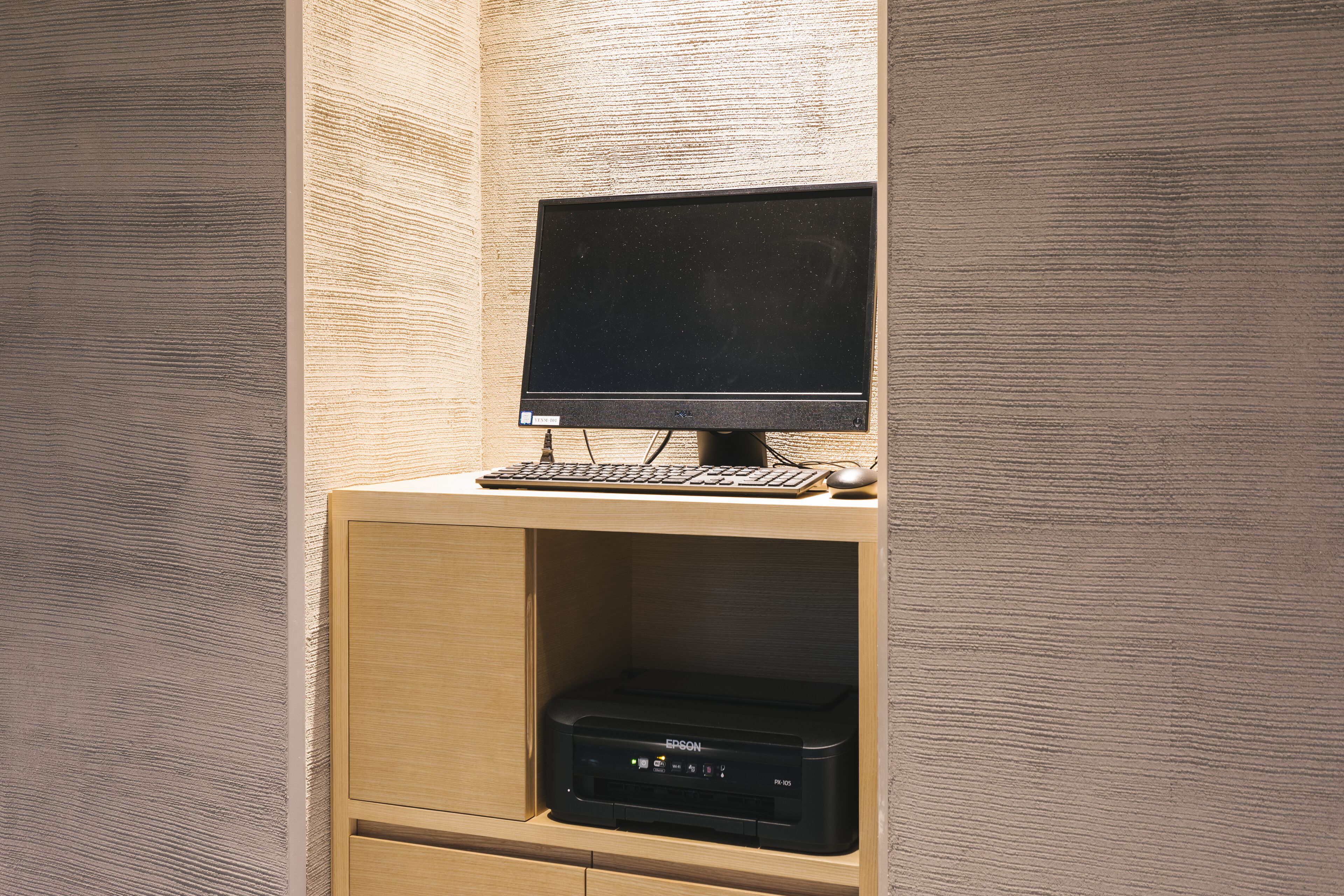 A computer desk with a monitor, keyboard, and mouse, and a printer below.
