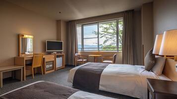 Quarto de hotel com cama, escrivaninha, cadeira, televisão e janela com vista.