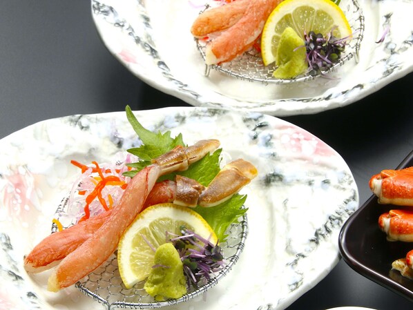 Two plates with seafood, lemon slices, and greens on a marble table.