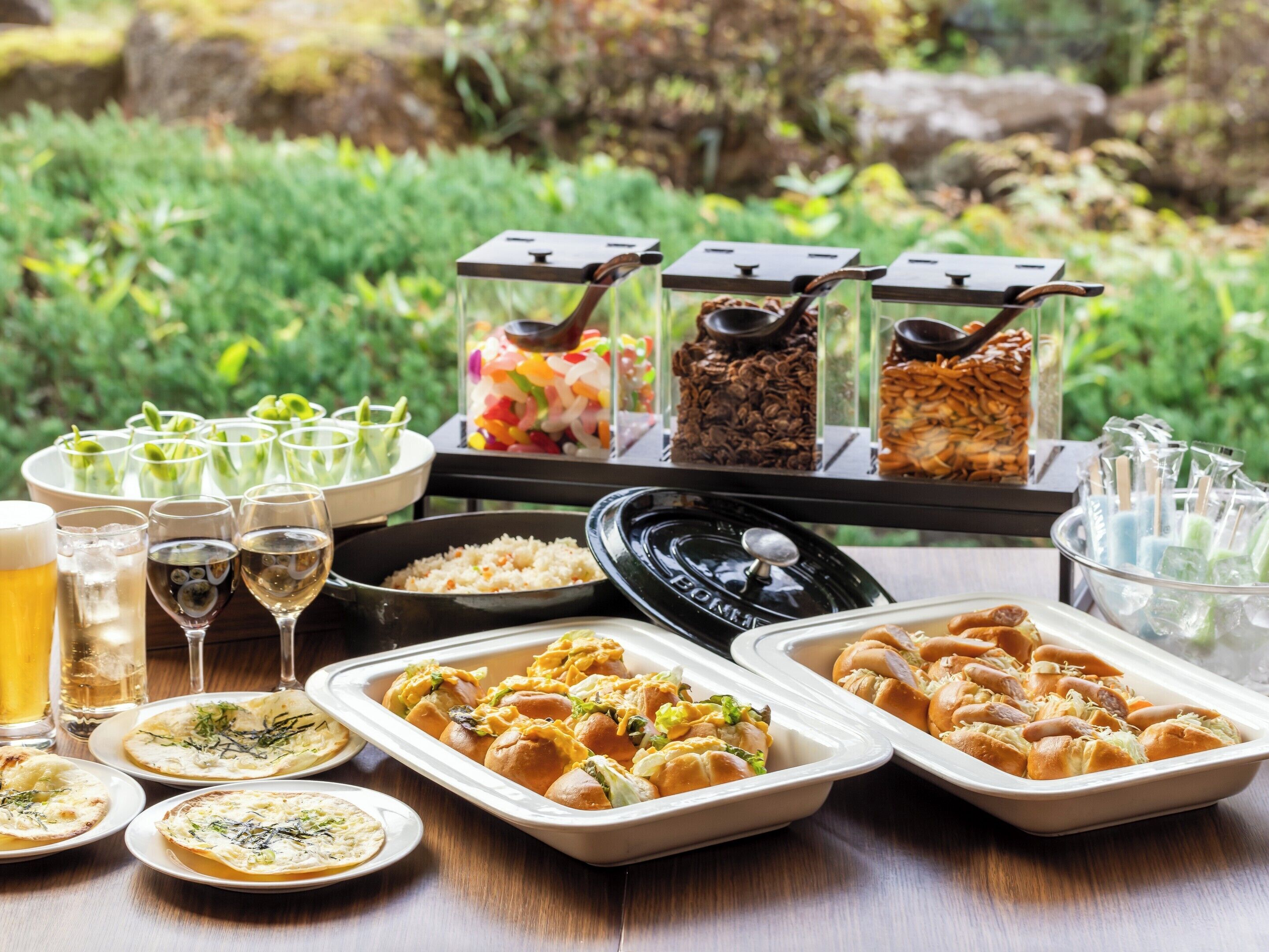 Een buffet met diverse gerechten en dranken, waaronder broodjes, salades en drankjes.