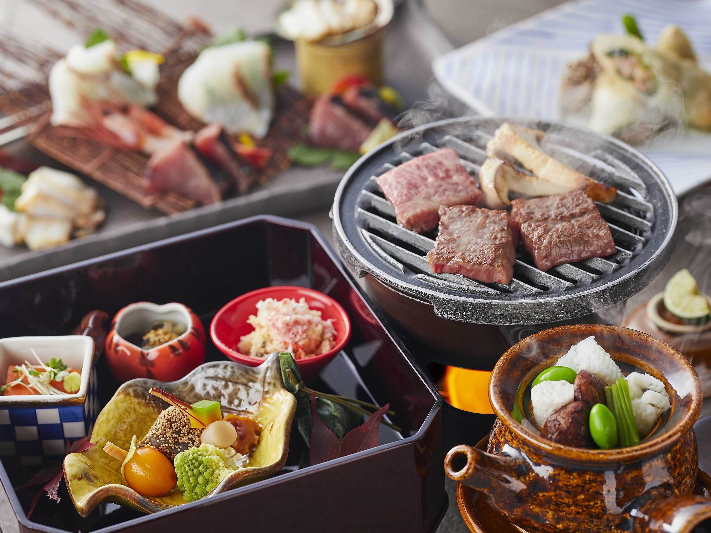 A variety of dishes including grilled meat, vegetables, and a hot pot.