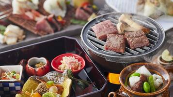 A variety of dishes including grilled meat, vegetables, and a hot pot.