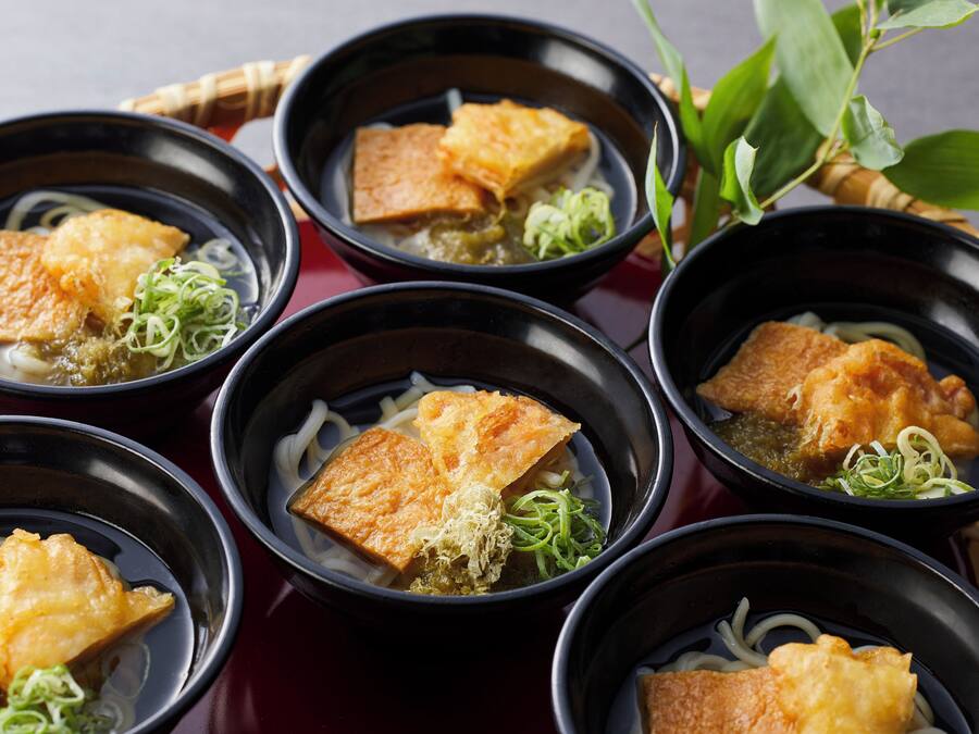 Des bols remplis de nourriture, notamment du tofu et des nouilles, disposés sur une table.