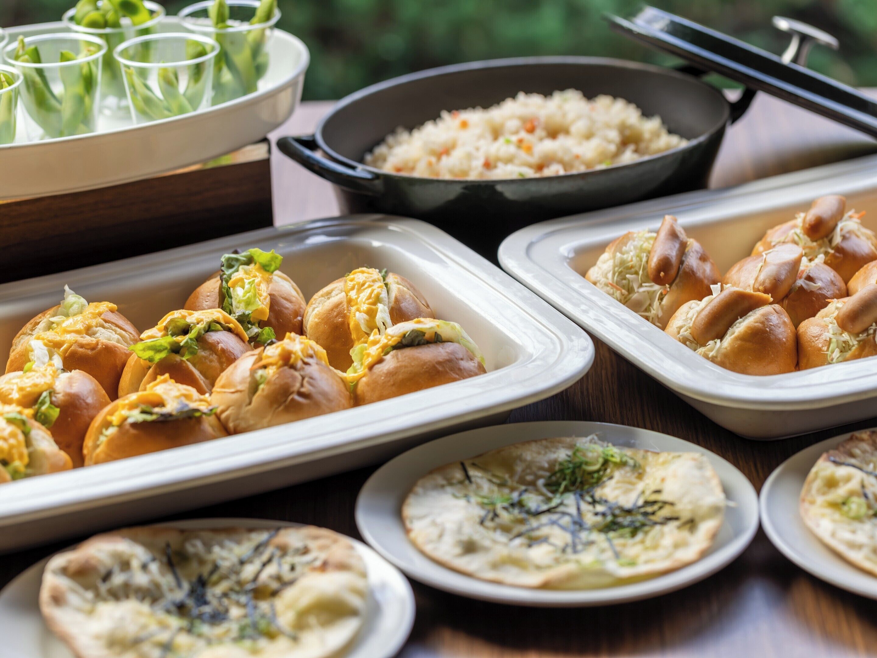 A buffet with various dishes including rolls, rice, and flatbreads.