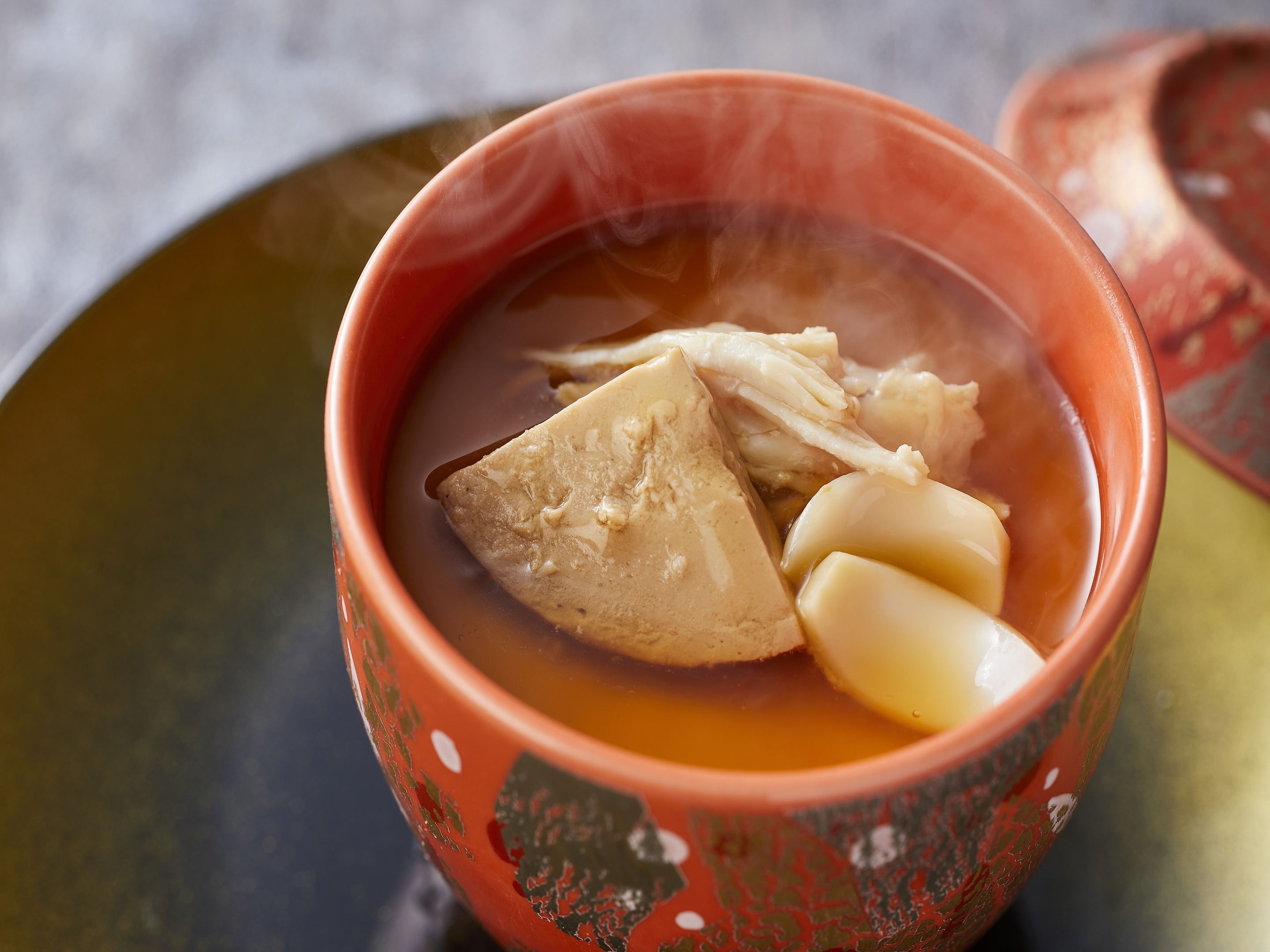 Un tazón de sopa con tapa, sobre una mesa.