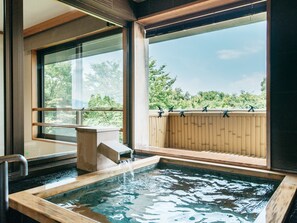 A hot tub area with a wooden deck and a view of trees outside.