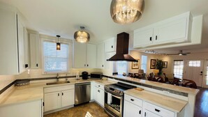Une cuisine moderne avec des meubles blancs, une cuisinière en acier inoxydable et un grand îlot central doté de sièges.