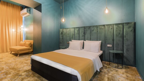 Une chambre à coucher comprenant un lit, une chaise, une table de chevet et un luminaire suspendu.