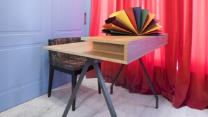 Une pièce avec une table en bois, une chaise à motifs léopard et un éventail coloré.