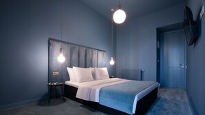 Une chambre à coucher moderne avec un lit, des tables de chevet et un téléviseur fixé au mur.