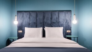 Une chambre moderne avec un grand lit, deux tables de chevet et des lampes suspendues.