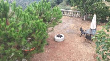 A patio area with a stone table and chairs, surrounded by greenery and a stone balustrade.