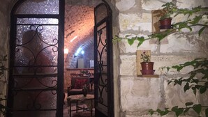 Un interior rústico de piedra con comedor, chimenea y plantas en macetas.