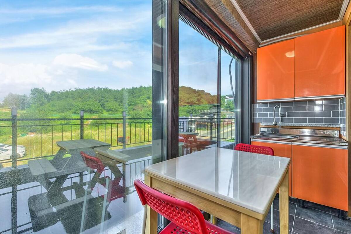 Cocina moderna con armarios naranjas y un amplio ventanal con vistas panorámicas.