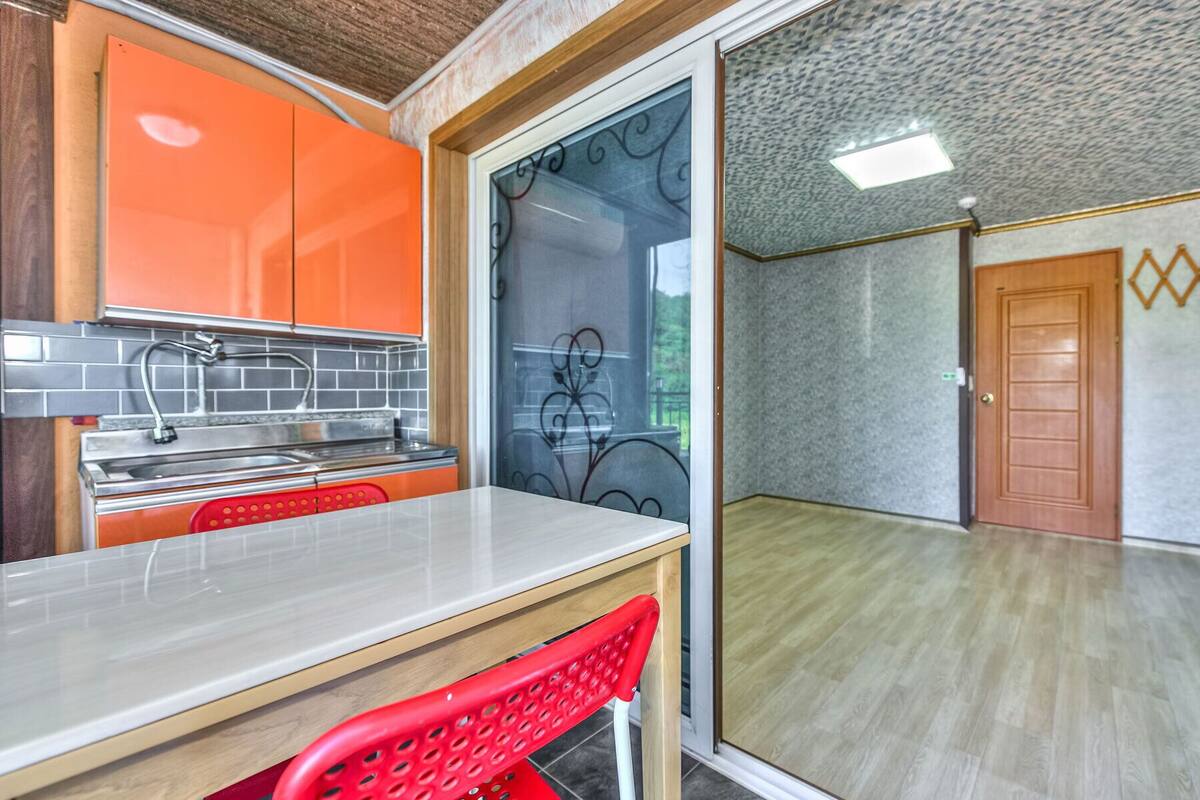 Una cocina moderna con gabinetes naranja, un lavamanos de acero inoxidable y una silla roja.