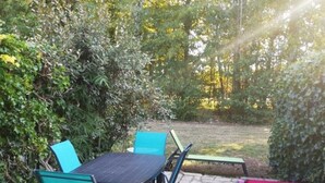 Une terrasse extérieure avec un sol en pierre et une table entourée de chaises.