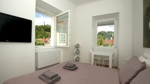 Une chambre à coucher avec un lit, deux fenêtres, une télévision et un bureau.