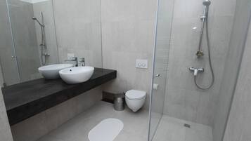 Une salle de bain moderne avec une douche à parois de verre, un lavabo blanc et des toilettes.