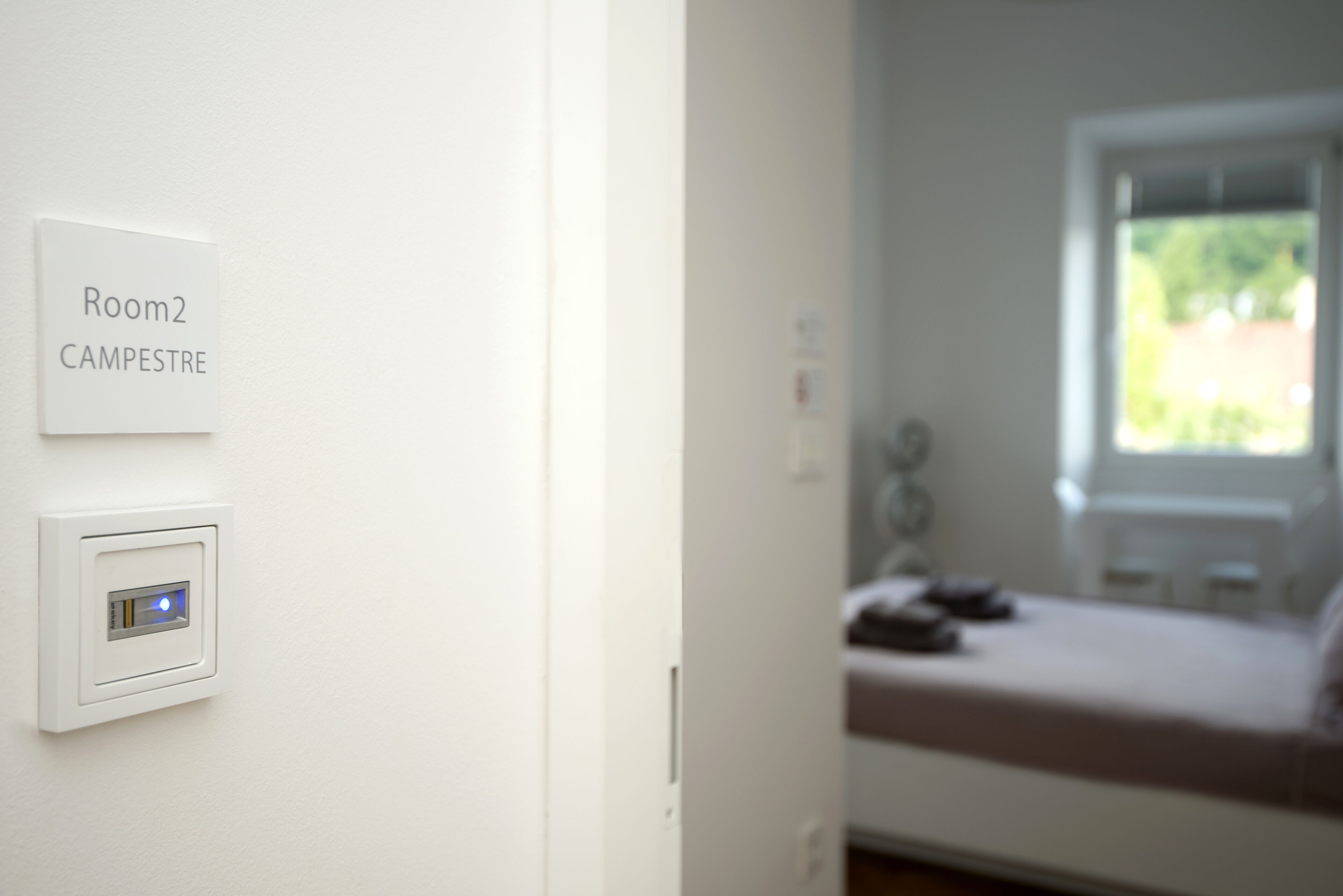 A white wall with a sign indicating "Room 2 CAMPESTRE" and a thermostat.