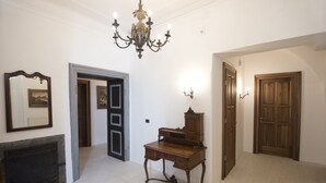 Una habitación con un escritorio de madera, un espejo, una lámpara de araña y una puerta.