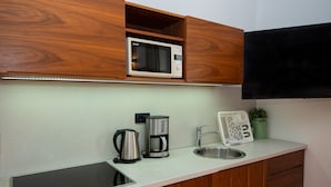 Una cocina equipada con microondas, cafetera y lavabo.