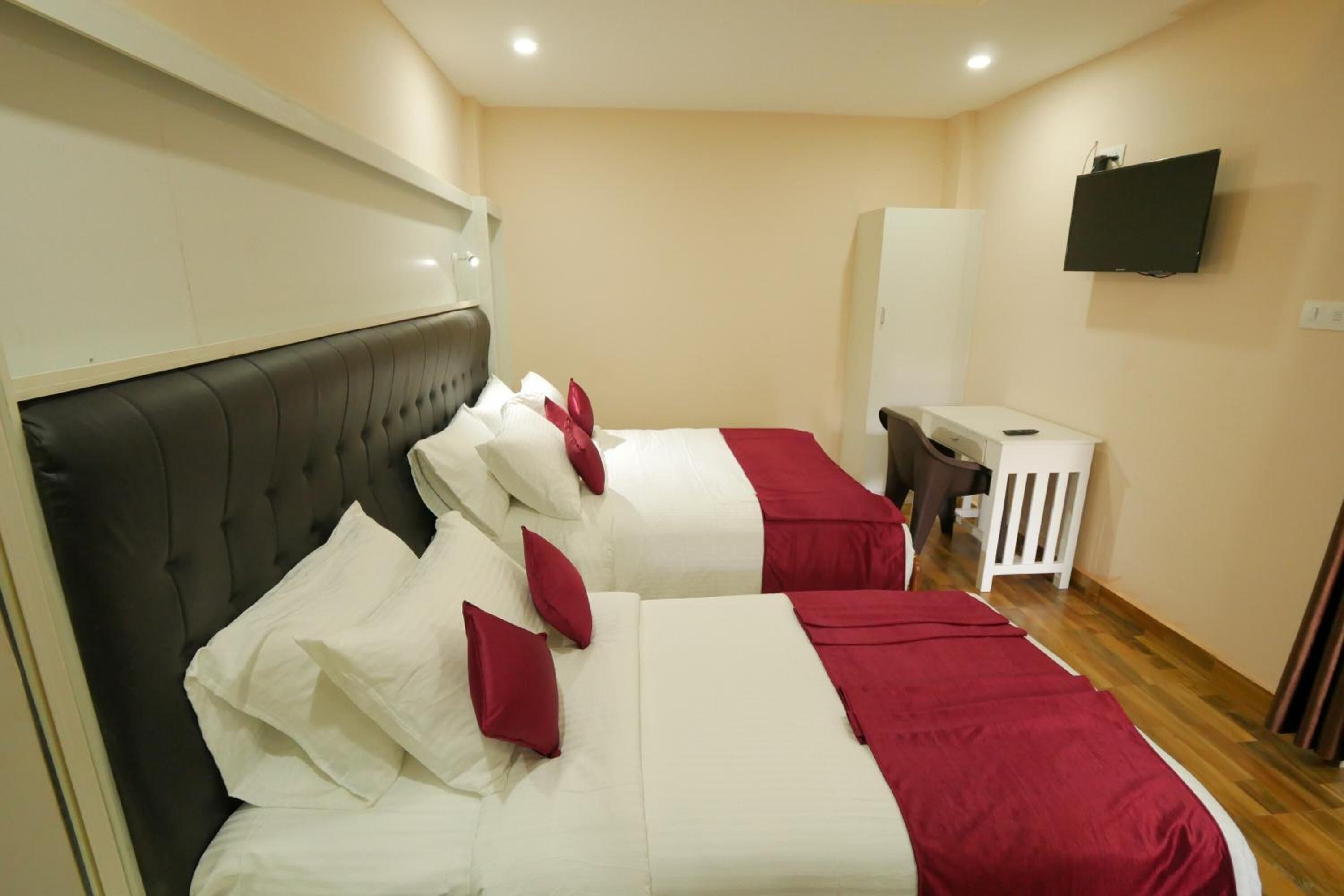 A hotel room with two beds, a TV, and a desk.