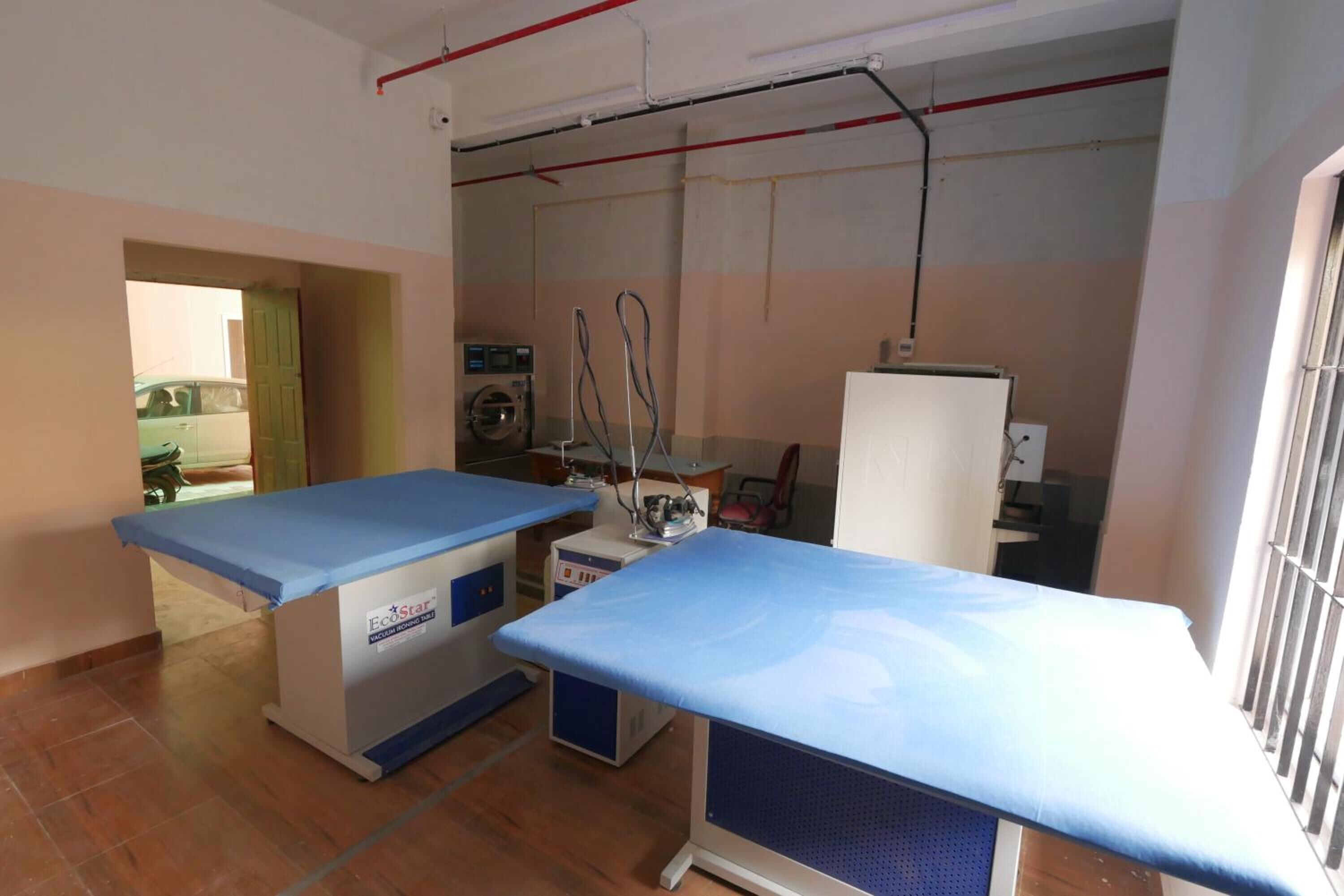 A medical examination room with two examination tables, a washing machine, and a refrigerator.