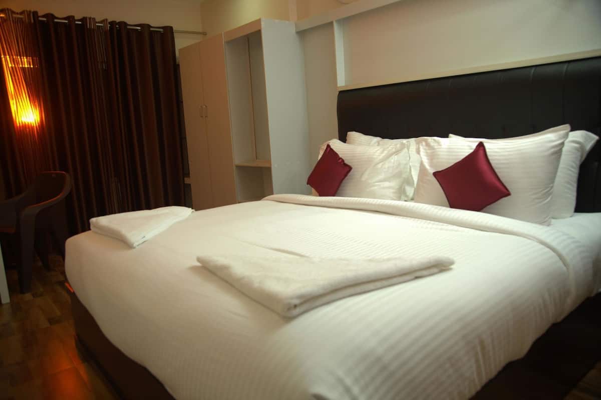 Habitación de hotel con una cama grande, un cabecero y un área de descanso con una silla.