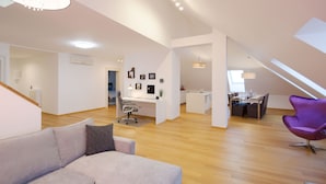 A spacious loft with a high ceiling, a dining area, and a modern office space. - VIP Apartment (Ljubljana)