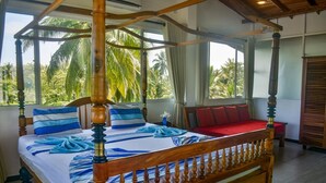 A four-poster bed with a canopy, a red bench, and a view of palm trees through large windows. - Southern Coastal Villas (Hikkaduwa)