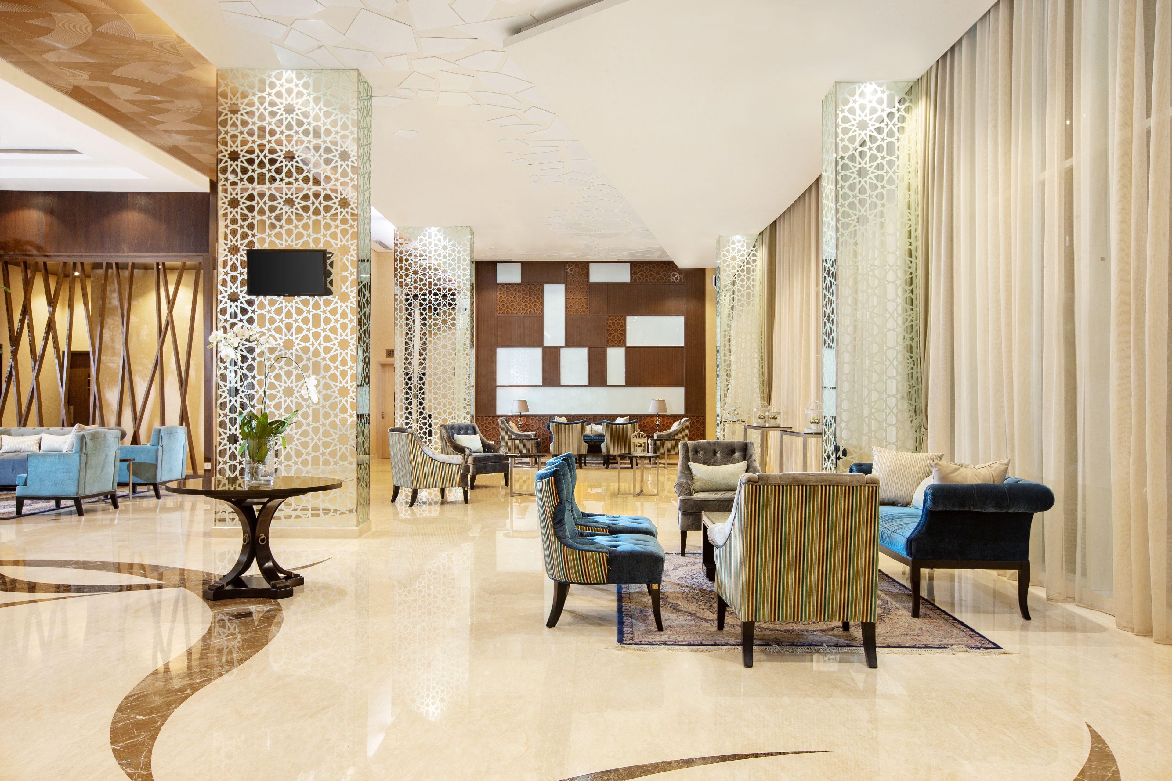 A spacious lobby with a modern design, featuring a mix of seating arrangements and a central area with a table and chairs.