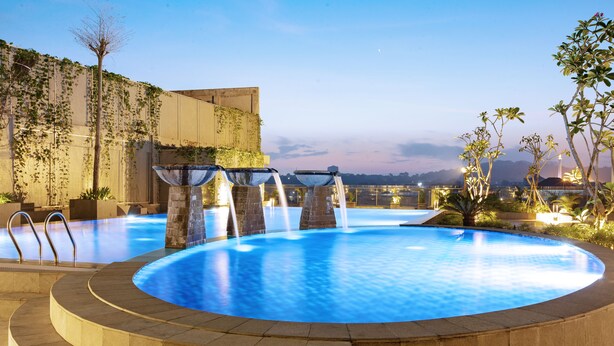A swimming pool with a circular design, surrounded by stone steps and a low wall. - Hotel Santika Gresik (Gresik)