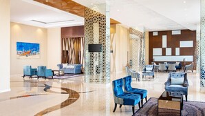 A spacious lobby with modern seating arrangements, a large flat-screen TV, and decorative panels. - Hotel Santika Gresik (Gresik)