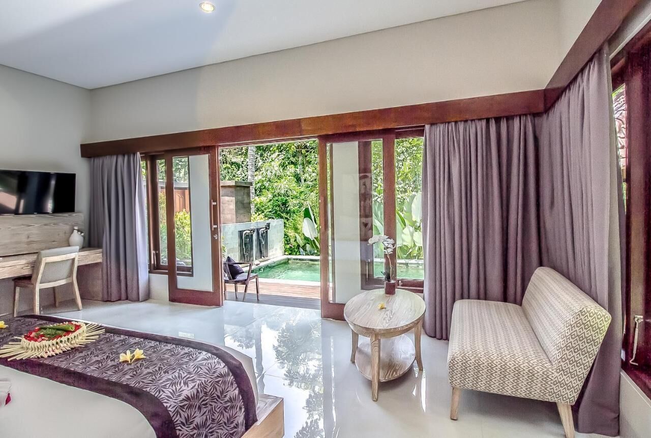 A spacious bedroom with a large bed, a desk, a TV, and a balcony with a pool.