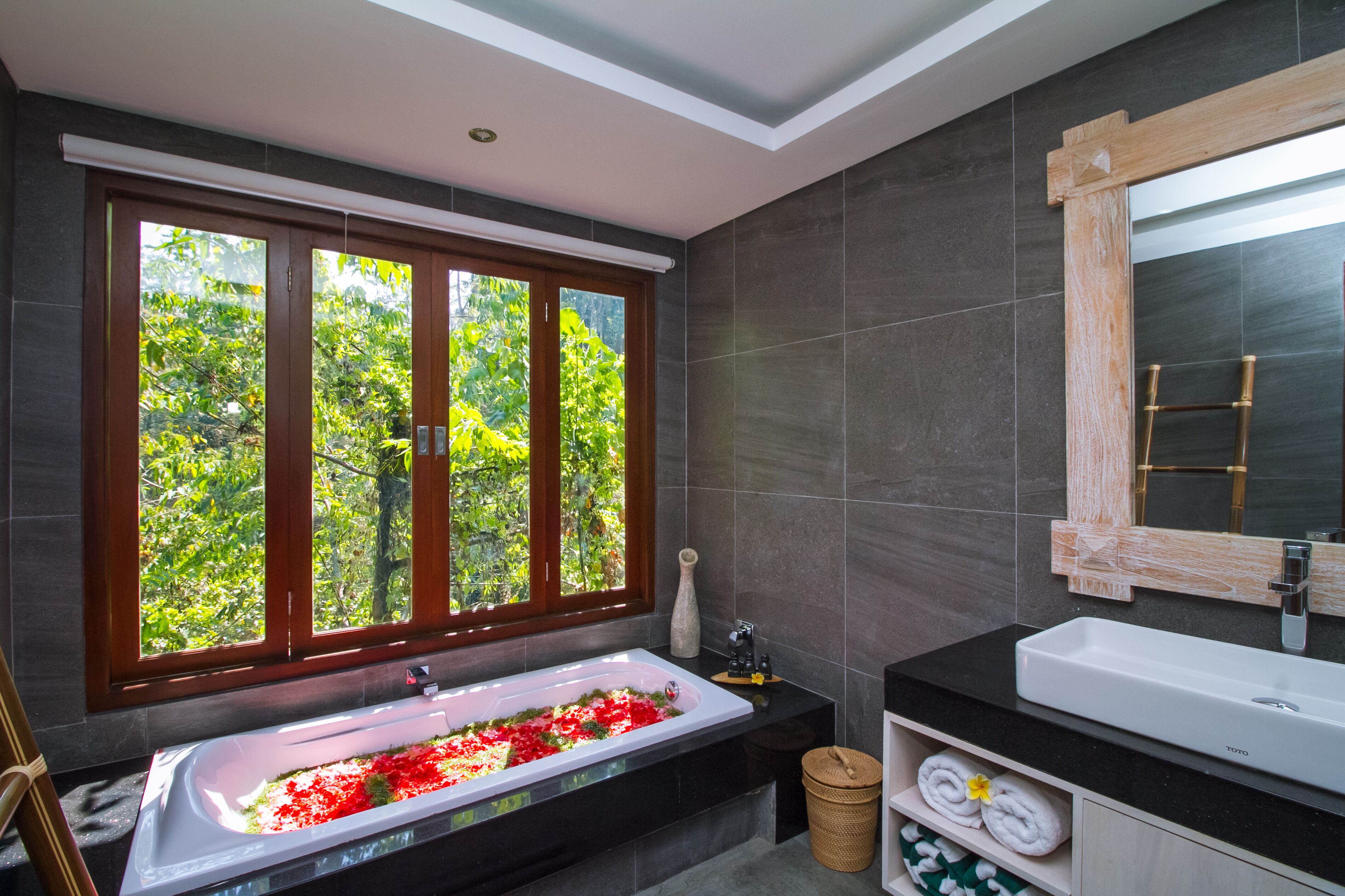 Un baño moderno con un ventanal grande, una bañera independiente, un lavabo y un espejo.